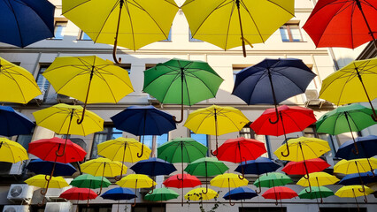 Fototapeta na wymiar multi color umbrellas as street outdoor decoration, bright blue sky background 