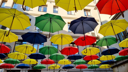 Fototapeta na wymiar multi color umbrellas as street outdoor decoration, bright blue sky background 