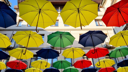 multi color umbrellas as street outdoor decoration, bright blue sky background 