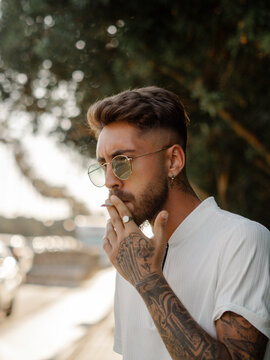 Hombre joven con tatuajes fumando