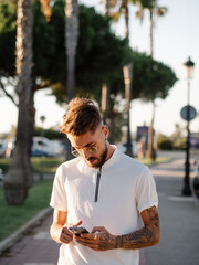 Hombre joven con tatuajes usando su teléfono móvil