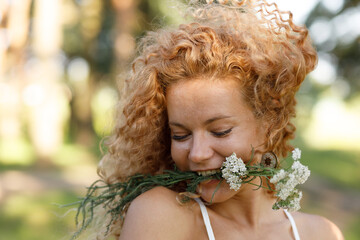 the girl is playful and happy with a bouquet of flowers in summer