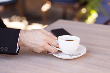 a man's hand holds a coffee mug at the table