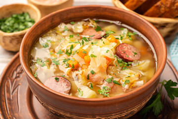 Polish sauerkraut soup Kapusniak in bowl on wooden background