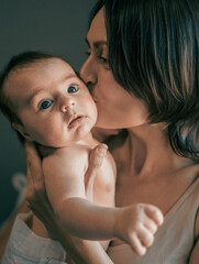 Mom, mummy, young mother with little baby daughter. Mum kissing and hugging child. Newborn cute happy girl smiling in woman hands. Happiness for parents in family. Aged parents, parenting, motherhood