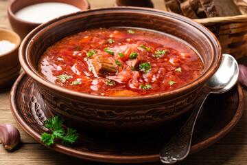 Traditional Ukrainian soup borscht in bowl on wooden background