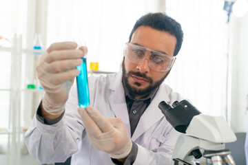 scientist doing research on plants holding a green solution in a test tube