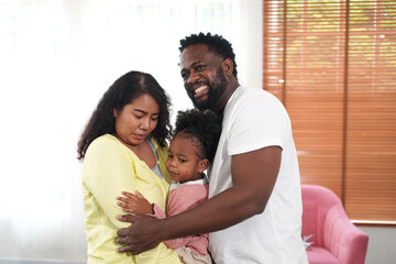 Shot of happy interracial family of mother father and their daughter inside modern apartment.