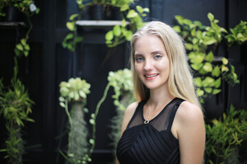 Positive woman with long blond hairstyle against green background, smiling and posing on background of vineyards