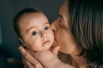 Mom, mummy, young mother with little baby daughter. Mum kissing and hugging child. Newborn cute happy girl smiling in woman hands. Happiness for parents in family. Aged parents, parenting, motherhood