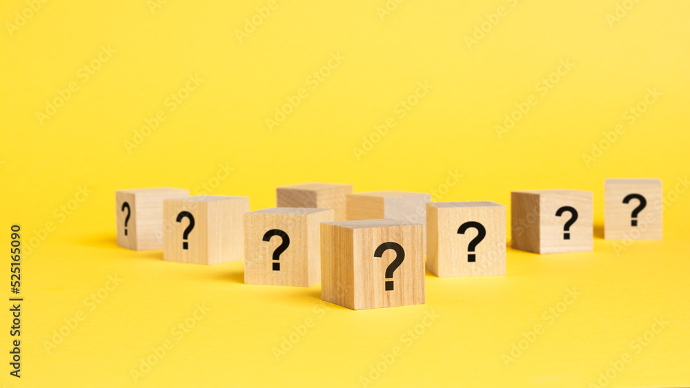 Poster front view on many wood cubes with question marks. many question arising concept, yellow background