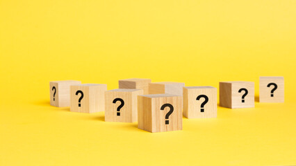 front view on many wood cubes with question marks. many question arising concept, yellow background