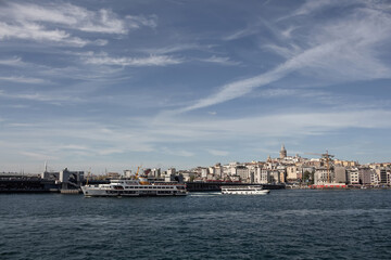 Fototapeta na wymiar View of a traditional ferry boat and tour boat on Golden Horn part of Bosphorus in Istanbul. Galata tower and Beyoglu district are in the view. It is a sunny summer day.