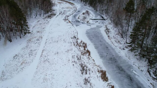 flight along the winter river and forest, aerial view of the winter landscape. snow and ice on the river