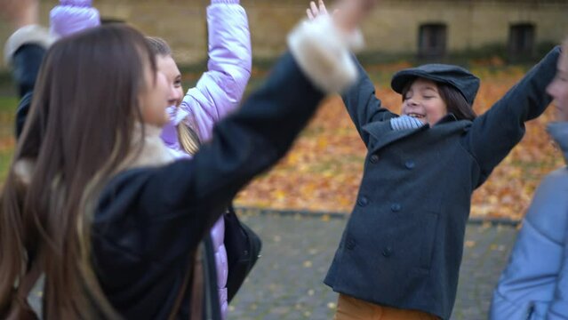 Teenage girls and boy stacking hands smiling standing on autumn schoolyard. Happy confident Caucasian classmates outdoors. education and friendship support