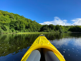 Kayak gonflable sur un lac paisible l'été. Pointe d'un canot jaune sur une rivière entourée de...