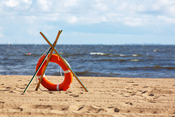An orange lifebuoy lies on the seashore. The concept of rescue on the waters.