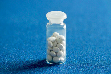 glass container with pills on a blue background