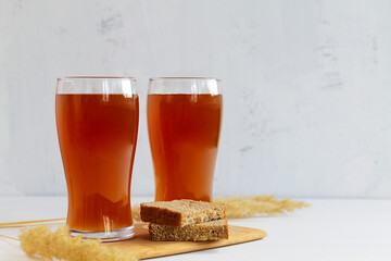 summer iced drinks. glass of beer and bread on the cutting board. two high Glasses of fresh kvass with bread on white background with copy space.