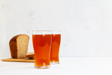 glass of beer on wooden table. two high Glasses of fresh kvass with bread on white background with...