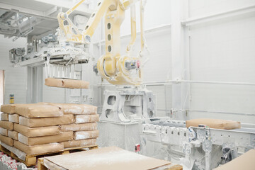 Huge hydraulic industrial machine lifting heavy packages and putting them on production line in...
