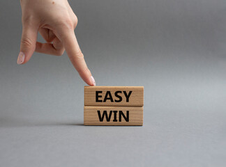 Easy win symbol. Wooden blocks with words Easy win. Beautiful grey background. Businessman hand....