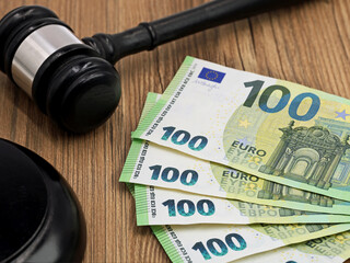 Judge gavel or auction hammer and hundred euro money banknotes on wooden table, concept image of...