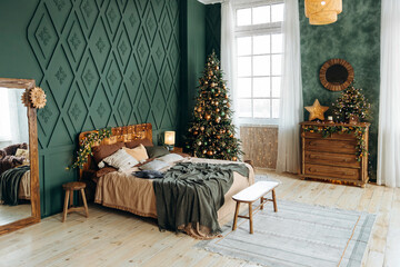 Bedroom decorated for Christmas. Bedroom interior with green walls, double bed and green Christmas tree decorated with emerald and bronze balls and gift boxes on th floor. Christmas interior. Nobody