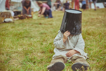 The boy fooling around puts a bucket on his head