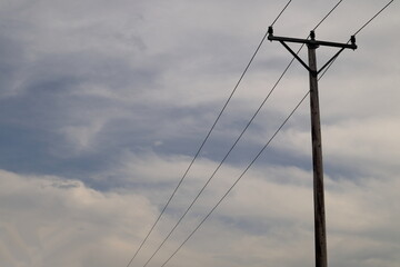 Power lines one cloudy day. Old wooden poles with 0,4 kV electricity distribution. Copy space. Sweden.