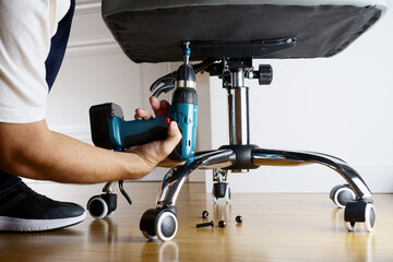 Master repairs office chair with a screwdriver