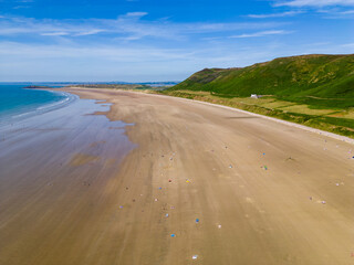 Fototapeta na wymiar Aerial view of tourists on a huge, wide sandy beach on the coast of Wales (Rhossili, Wales)