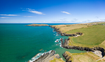 Aerial view of a tiny sandy beach surrounded by cliffs on the coast of Wales (Gwbert, Pembrokeshire)