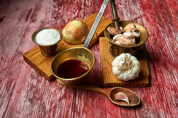 kitchen utensils such as boards, wooden spoon, saucepan with vinegar, brass starches, garlic, salt and onion