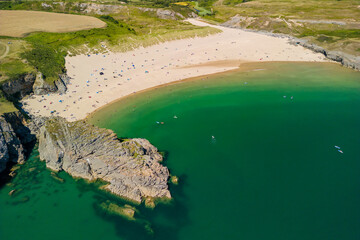 Aerial view of a large, busy sandy beach and rocky coastline in West Wales (Broad Haven South,...