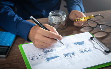 Fototapeta premium Man holding magnifying glass with a graphs and charts. Business. Analysis