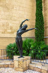 Sculpture of a nude woman posing in mid-air next to an alleyway