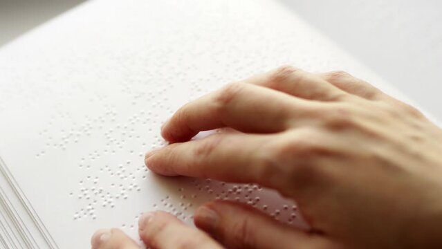 Poorly seeing woman learning Braille book. A person with blindness touches and reads with his hands.	
