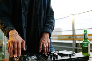 Hands of deejay in black shirt mixing sounds while standing in front of turntables and rotating one...
