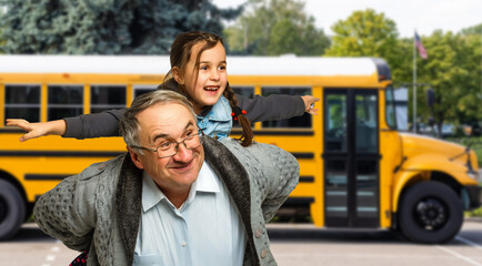 a little girl with her grandfather near the school bus