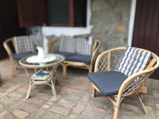 Closeup view of front porch coffee table with knitted wood chairs on rustic brick floor