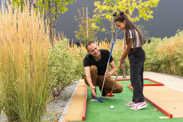 father and daughter playing mini golf