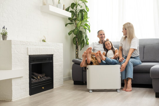 Family Warming Up Near Home Heater At Winter Cold Time. The Symbolic Image Of The Heating Season At Home.