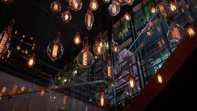 Beautiful loft-style chandelier on a dark ceiling background. A large loft-style chandelier with light bulbs at different heights. High quality FullHD footage