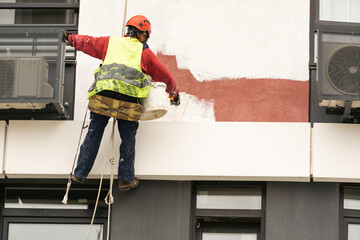 construction worker is painting a wall with a roller