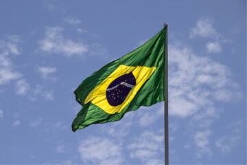 A bandeira do Brasil. Bandeira do Brasil voando, tremulando ao vento com céu azul e algumas nuvens...