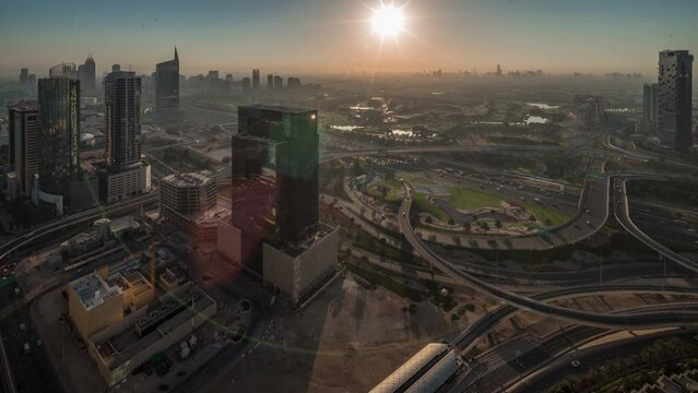 Aerial panoramic view of media city and al barsha heights district with golf course night to day transition timelapse from Dubai marina during sunrise. Towers and skyscrapers with traffic on a highway