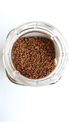 ISOLATED OPEN TRANSPARENT GLASS JAR OF INSTAT COFFEE ON WHITE TABLE, TOP VIEW, SELECTIVE FOCUS