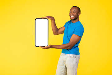 Black Man Holding Big Phone With Empty Screen, Yellow Background