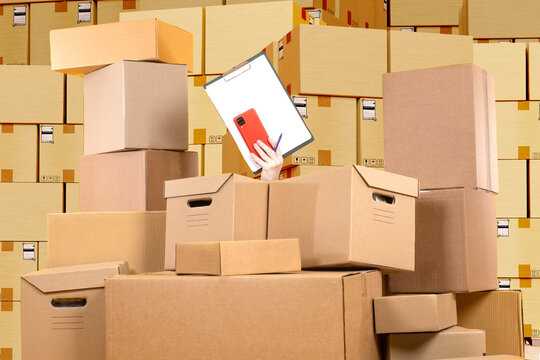 Stocktake at warehouse. Womans hand with clipboard. Chaos card boxes. Concept accounting courier boxes. Warehouse background. Stocktake boxes. Warehouse lot with chaos. Working in logistics business